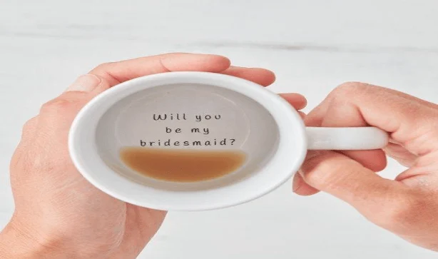 white mug with writing being held in two hands
