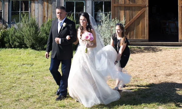 Day of Coordinator helping bride with Dres as she walks to alter with her father