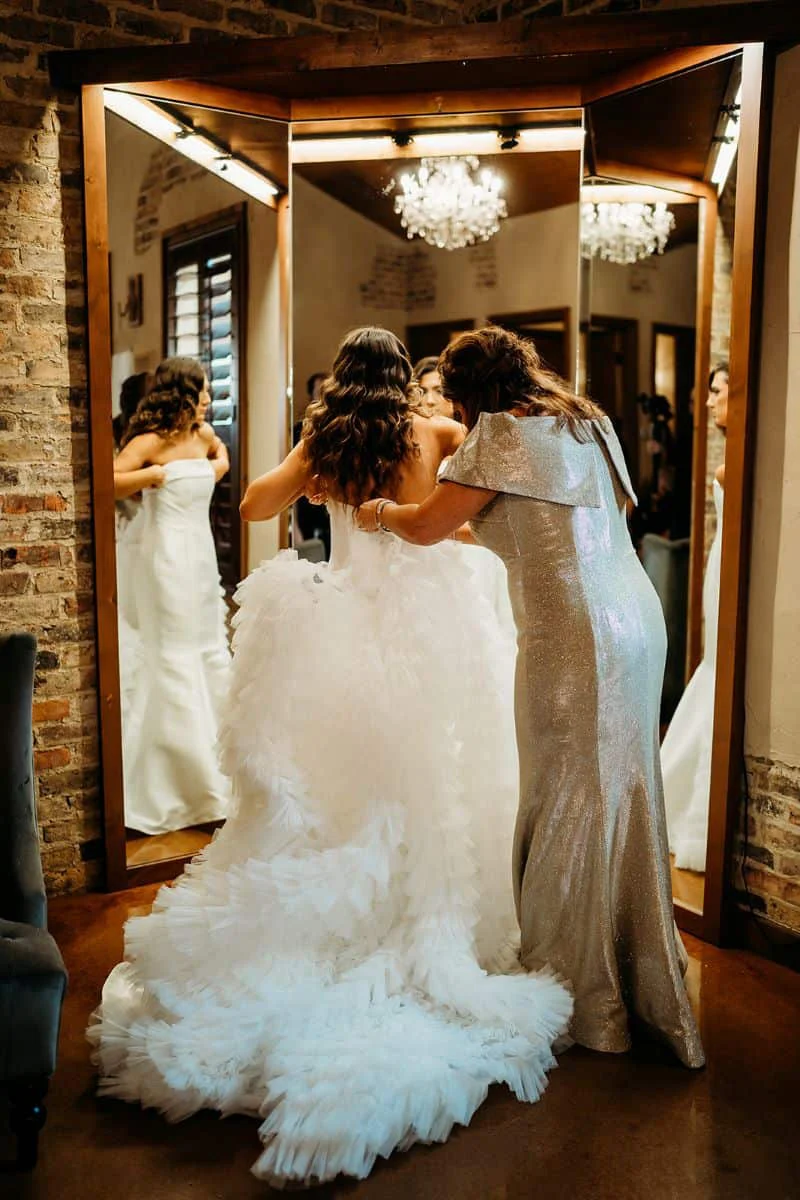 Mackenzie being helped into her gown in front of the mirrors