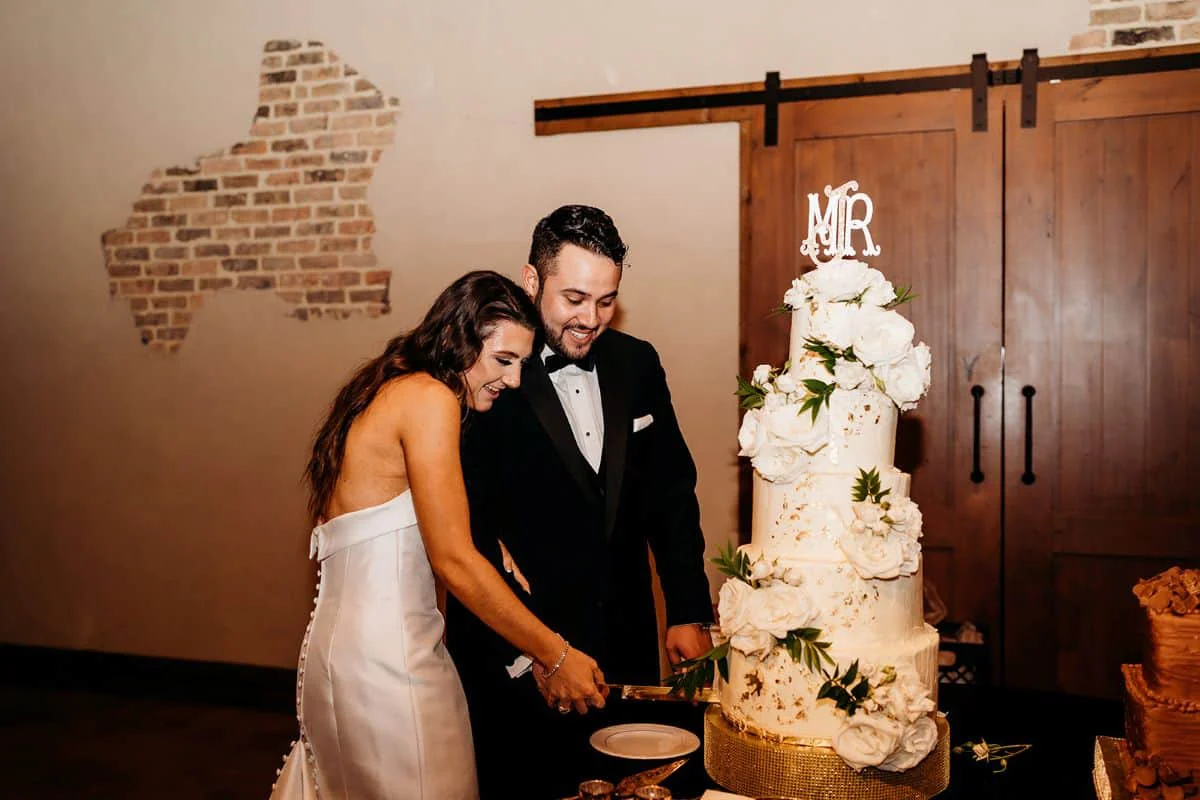 Cutting their four-tier cake dressed with white blooms