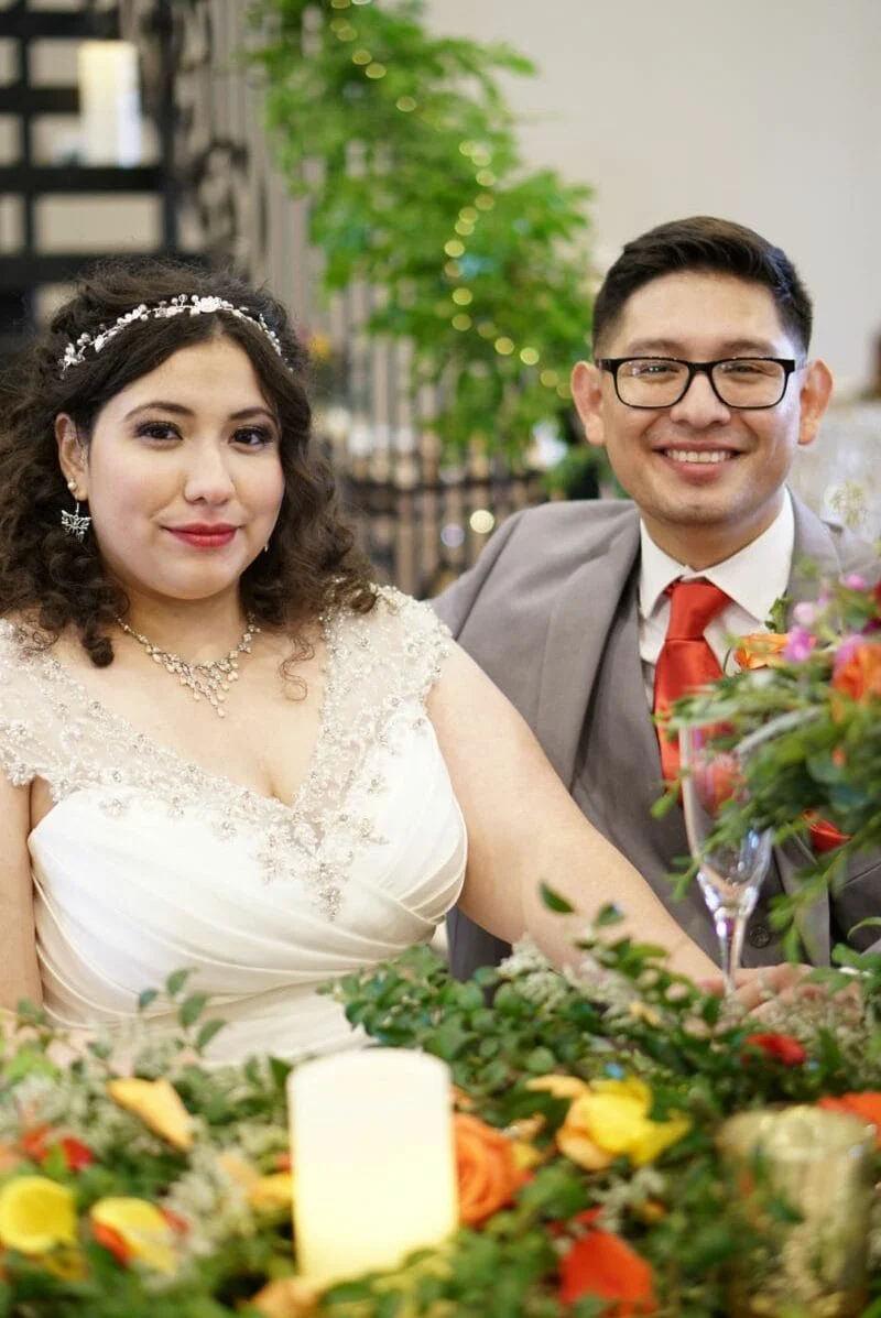 The couple at their sweetheart table among the candles and blooms