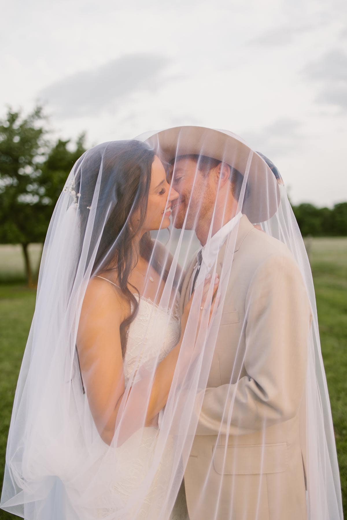 A wedding bride and groom embracing under her wedding veil