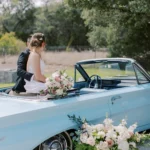 Bride and groom sitting on a wedding car rental on their wedding day