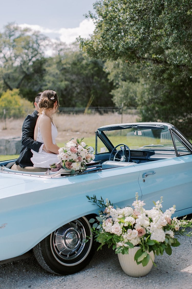 Bride and groom sitting on a wedding car rental on their wedding day