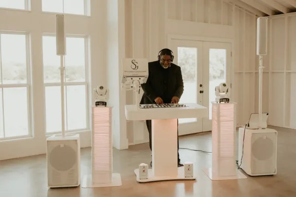 A full DJ setup with speakers, lighting towers and moving heads flanking the booth