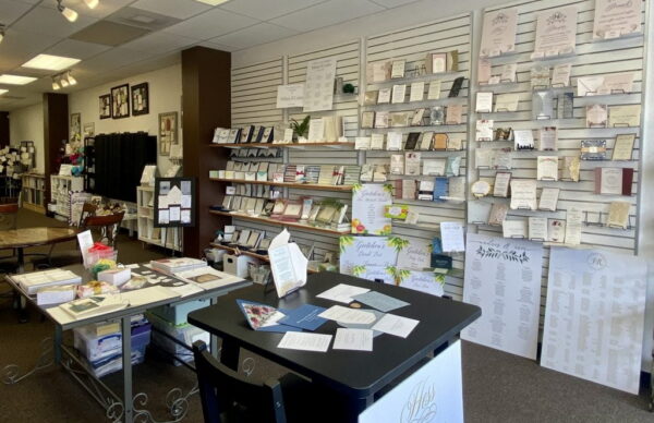 The Aly Am Paperie studio with invitation samples displayed across slatwall shelving and worktables