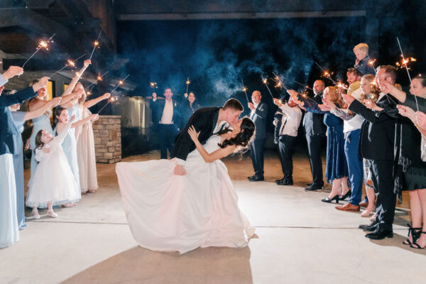 A couple kissing during a sparkler exit with guests lining both sides