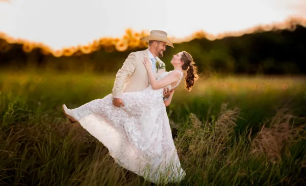 Wesley Cornelius lifting Jordyn in the tall grass at golden hour