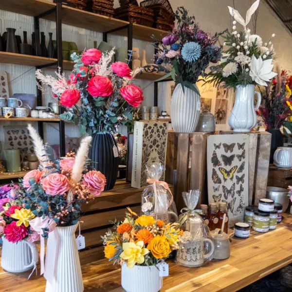 A shop display of wooden flower arrangements in vases on wooden shelving