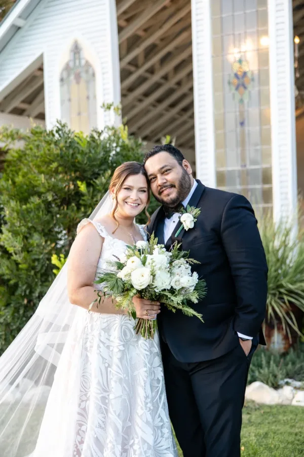 Erik and Emily Gonzalez outside the chapel with her white winter bouquet