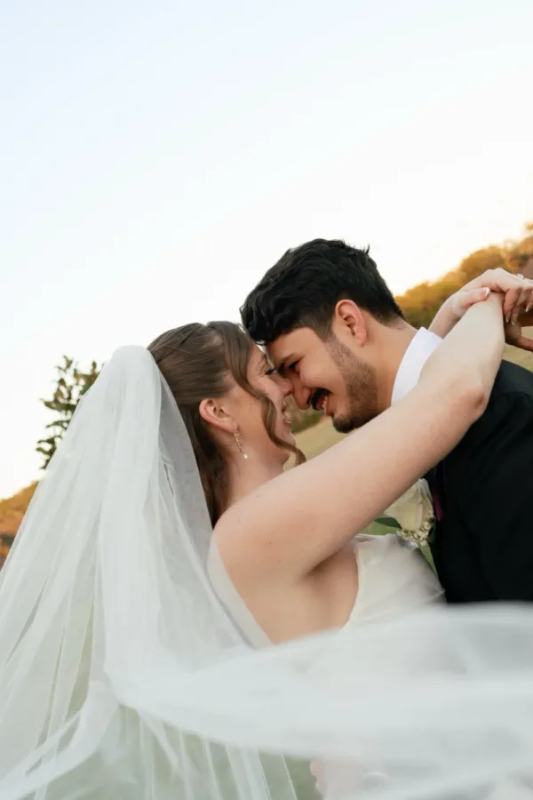 Nicolas and Kristen Huerta embrace at golden hour with her veil swept behind