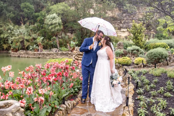 Jimmy and Alexandria Olsen under an umbrella beside the pond at the San Antonio Botanical Gardens
