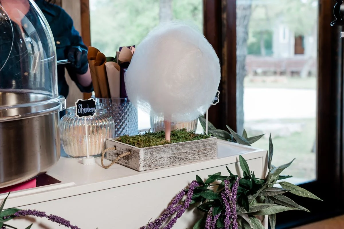 Fresh spun cloud of white cotton candy displayed on a moss lined stand on a serving cart