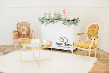 White Sugar Clouds cotton candy cart styled with vintage armchairs and a gold accent table