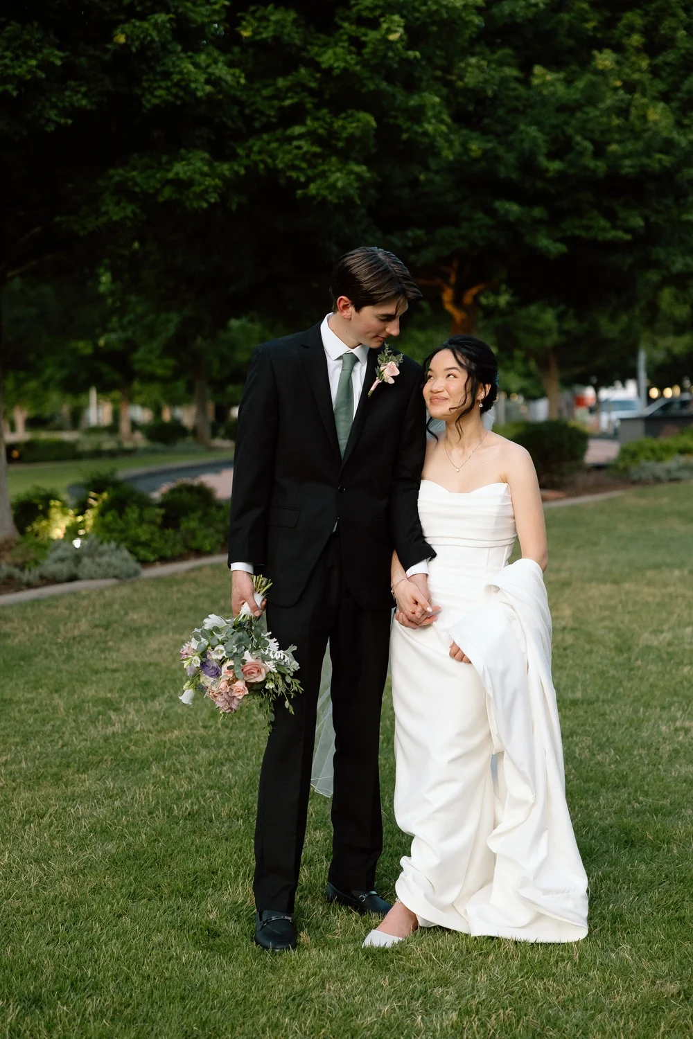 The couple walk across the lawn together at dusk after the ceremony