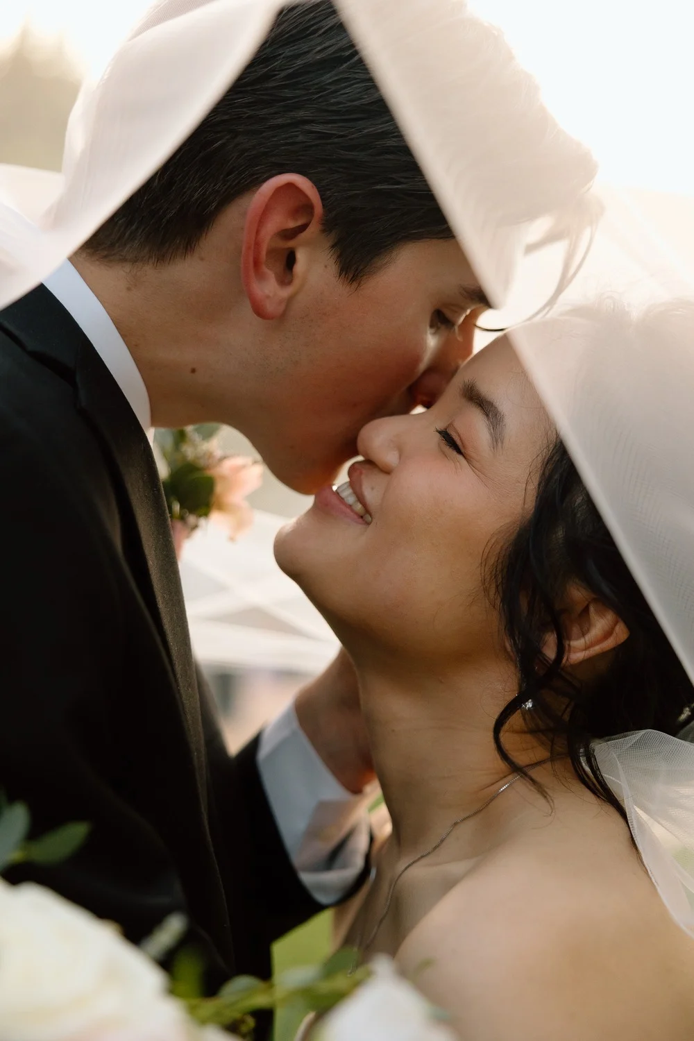 Close up of the bride and groom smiling together beneath her veil