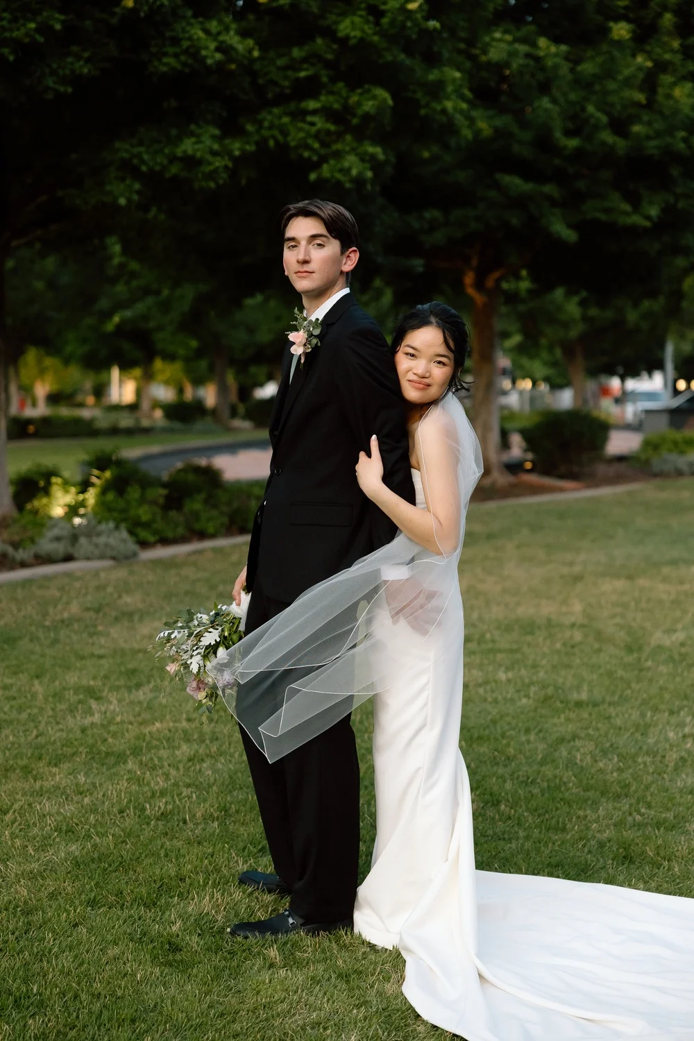 The newlyweds embrace on the lawn as the evening light fades