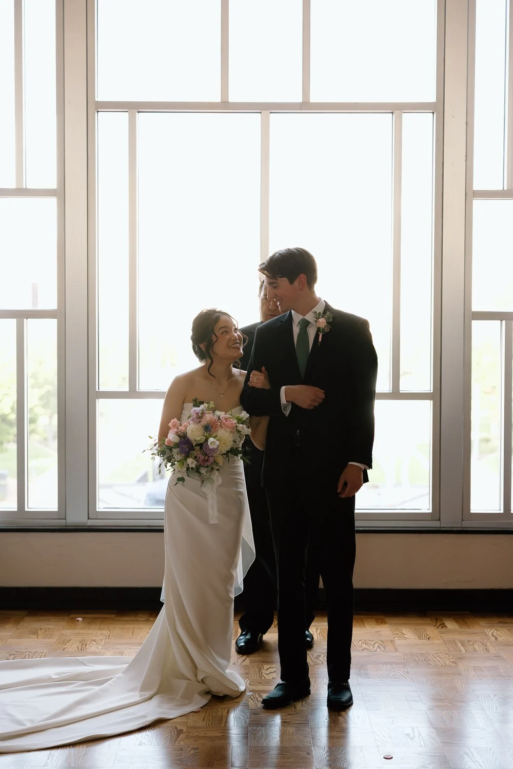 The bride and her father in front of the ballroom’s tall art deco window