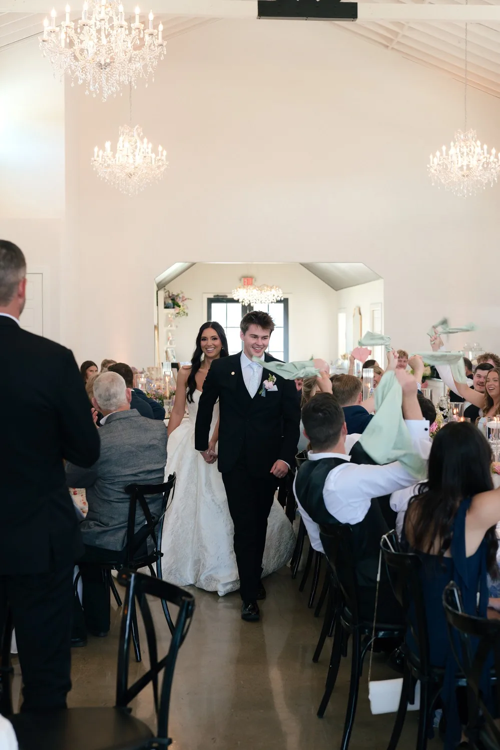 The couple's grand entrance into the reception hall as guests wave mint green napkins