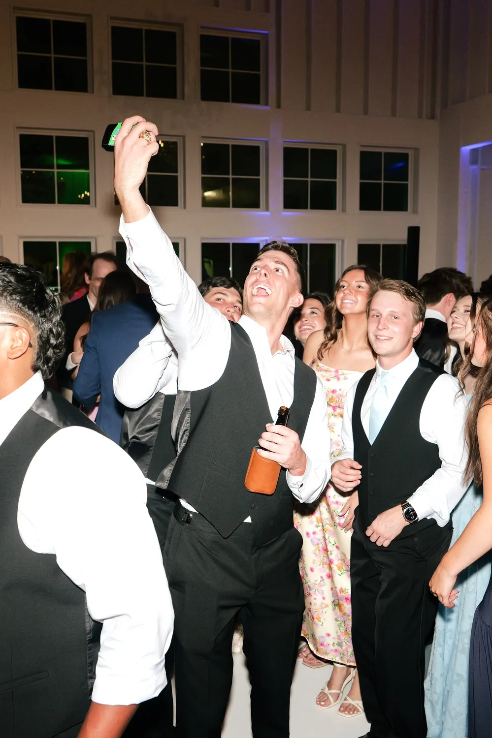 Groomsmen and guests crowd together for a selfie on the reception dance floor