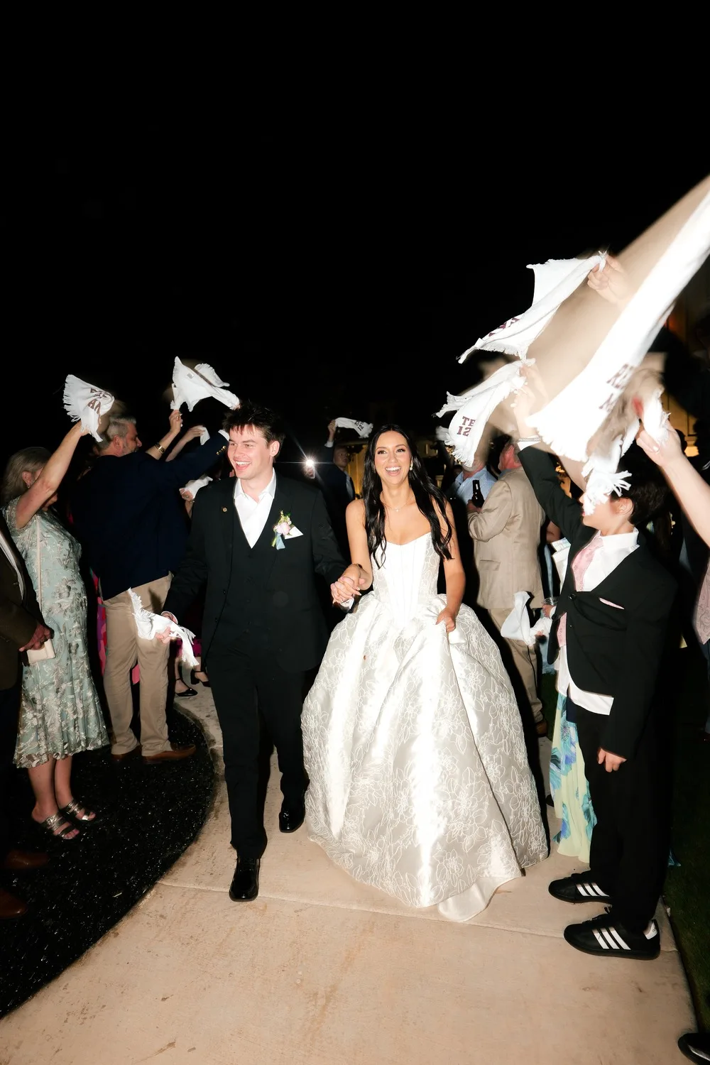 The newlyweds' grand exit through a crowd of guests waving white towels