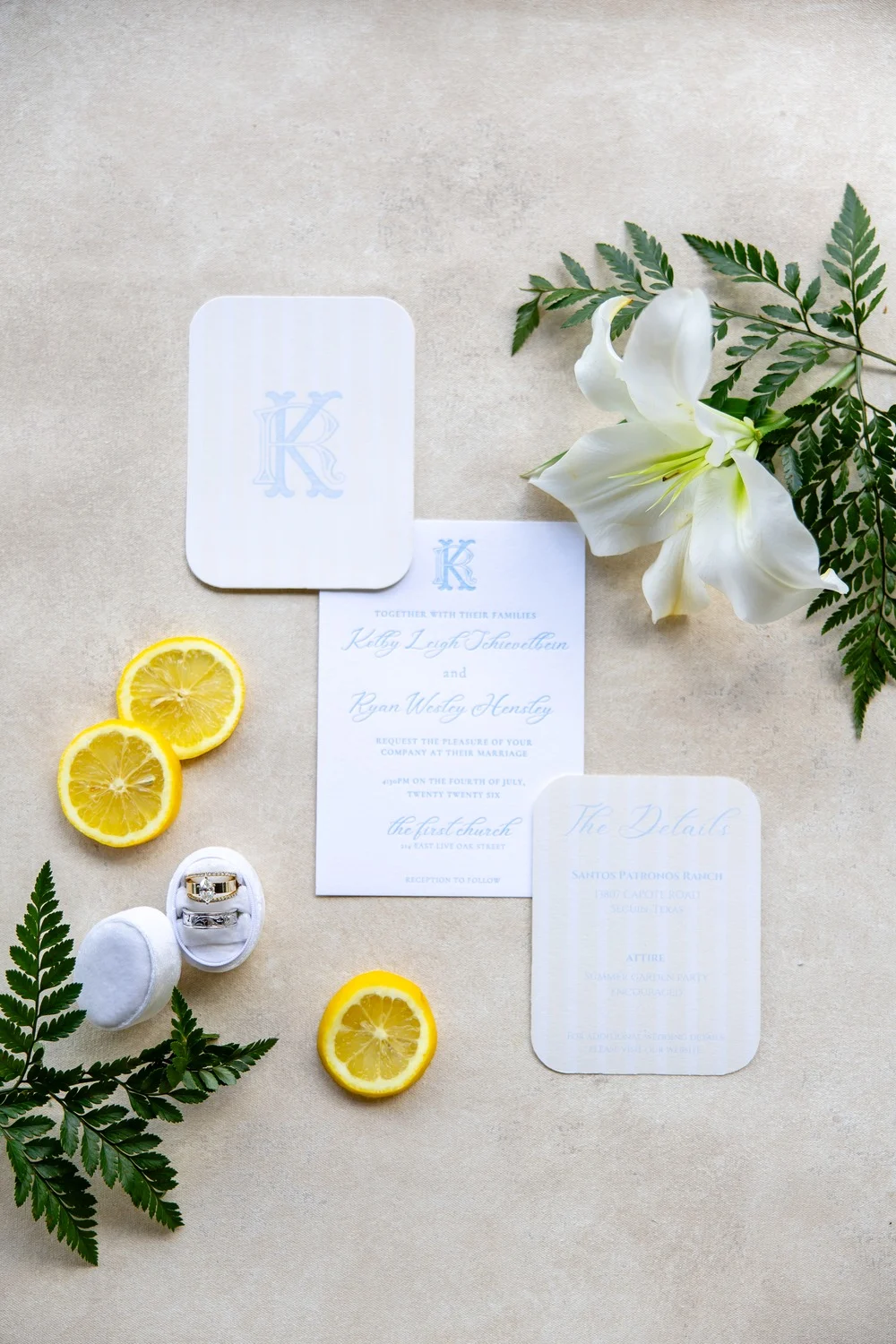 Blue monogrammed wedding invitation suite with lemon slices and greenery